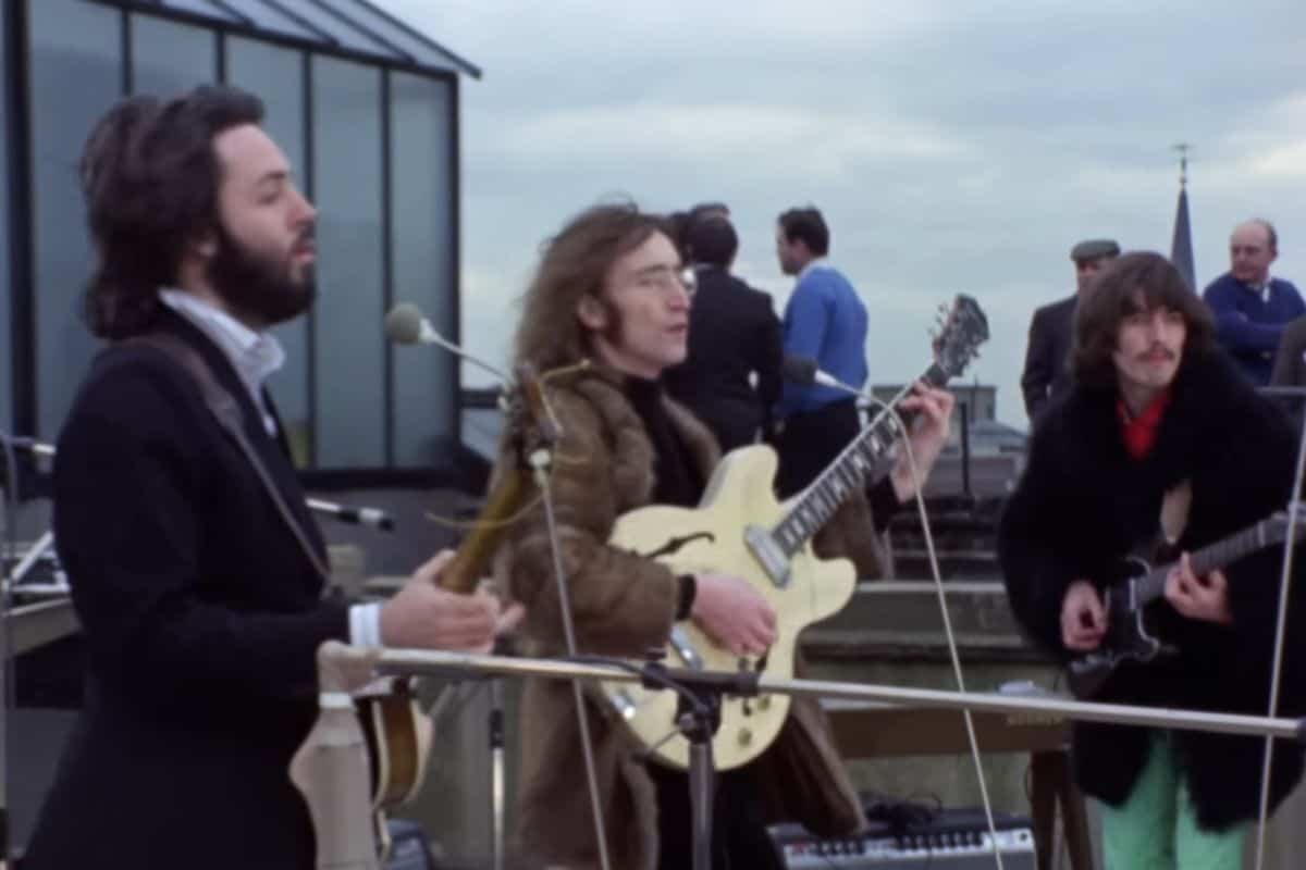 Vintage band performing rooftop concert with guitars and microphones.