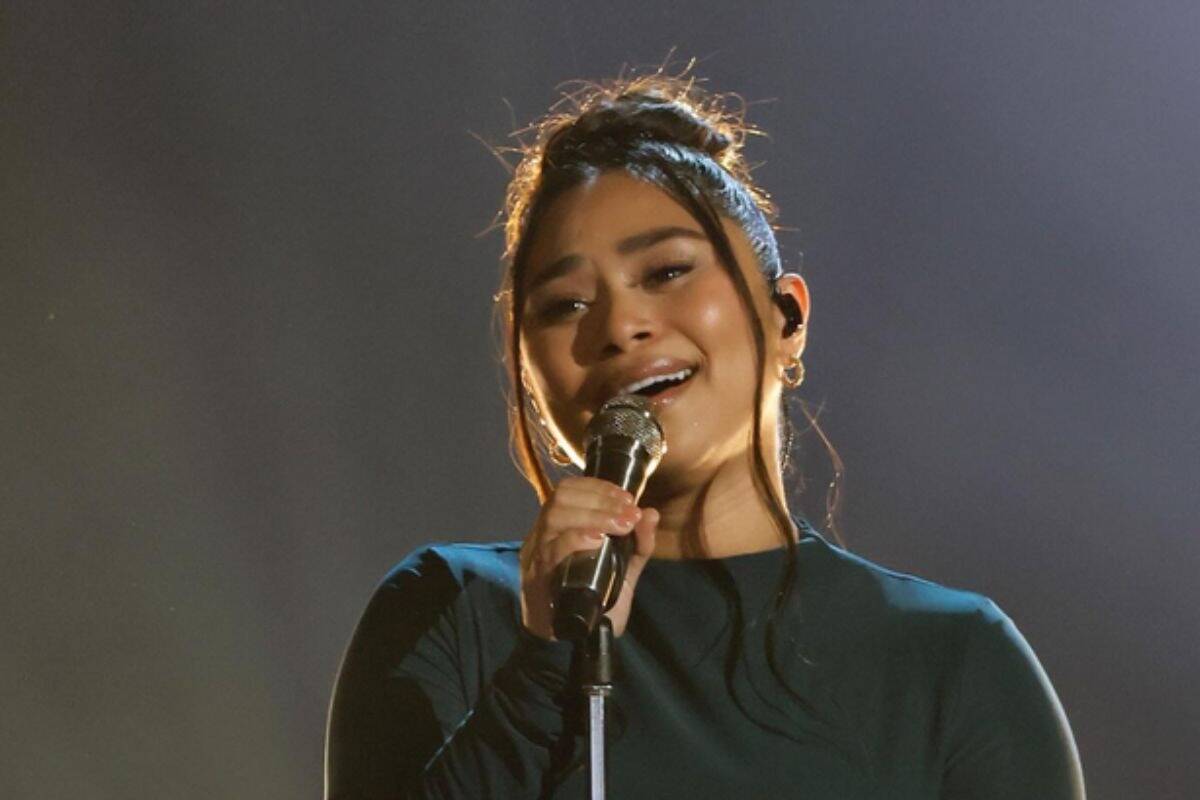 Portrait of a young woman singing into a microphone on stage at Viral Music FM.